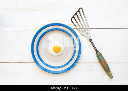 Frittura di uovo di quaglia su una piastra cornishware con una spatola vintage dal di sopra Foto Stock