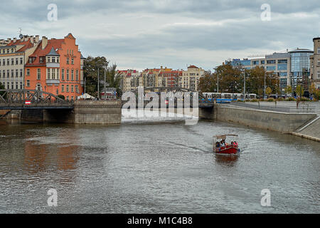 Vista dal ponte Tumski al ponte Mlynski (la maggior parte Mlynskiof ) con piccole imbarcazioni turistiche sul fiume Odra e un tram sul ponte. Wroclaw, Polonia Foto Stock