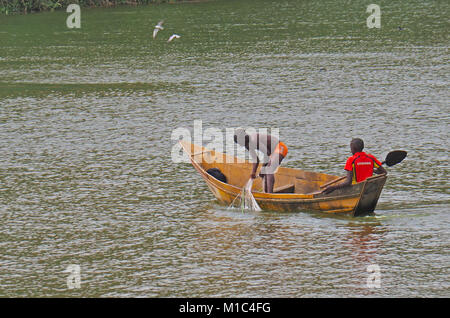 Giovani uomini ugandesi net pesca dalla piccola barca nel lago George, Uganda. Foto Stock
