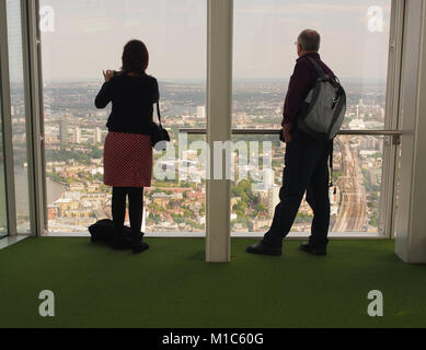 Un uomo e una donna che guarda oltre la zona est di Londra dal più alto piano di visualizzazione, 27, di Shard, Londra Foto Stock