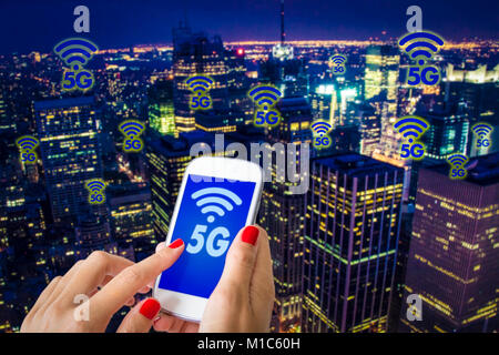 5G o LTE presentazione. Donna mano utilizza lo smartphone con la città moderna sullo sfondo Foto Stock