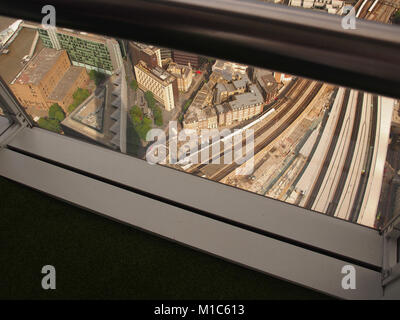 Una vista guardando verso il basso attraverso una finestra incorniciata dal piano più alto, 27, di Shard, Londra, per la stazione di London Bridge e i binari ferroviari Foto Stock