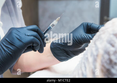 Plastica di contorno: medico dermatologo iniettare la carica. Close up mani femminili di cosmetologo rendendo iniezione nelle labbra. Cosmetologia estetica. Selective Foto Stock