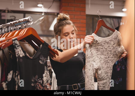 Bella donna selezionando i vestiti dalla cremagliera Foto Stock