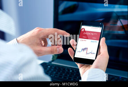 L'uomo controlli tassi bitcoin a smartphone applicazione forex. Interfaccia creata nel programma di grafica Foto Stock