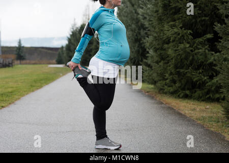 Donna incinta eseguendo stretching esercizio Foto Stock