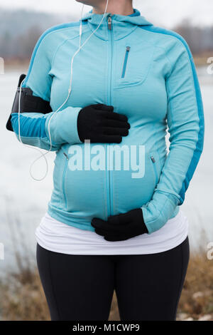 Donna incinta toccando il suo ventre nel parco Foto Stock
