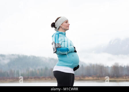 Donna incinta toccando il suo ventre nel parco Foto Stock