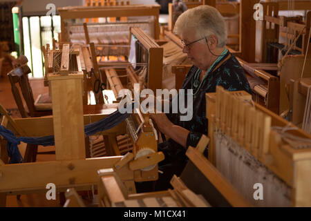 Senior donna seta tessitura al shop Foto Stock