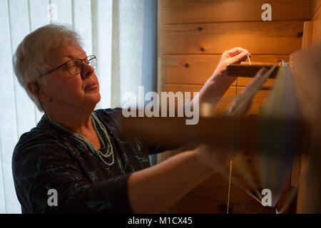 Senior donna seta tessitura al shop Foto Stock