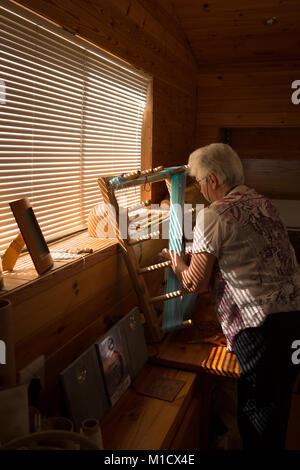 Senior donna seta tessitura al shop Foto Stock