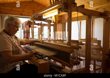 Senior donna seta tessitura al shop Foto Stock