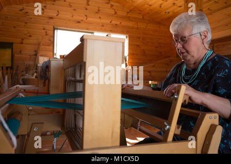 Senior donna seta tessitura al shop Foto Stock