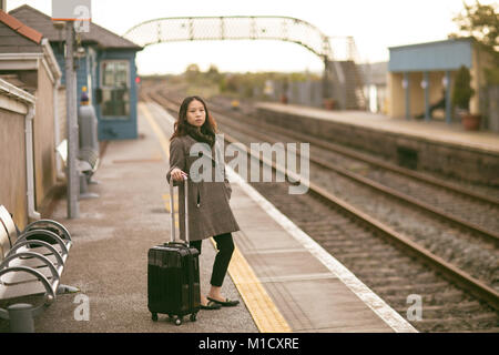 Executive femmina in attesa per i treni con i bagagli Foto Stock