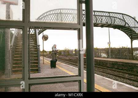 La donna in attesa per il treno con i bagagli Foto Stock