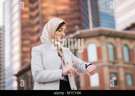 Donna in hijab utilizzando smartwatch Foto Stock