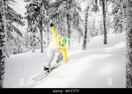 Uomo a cavallo di un snowboard nella foresta innevata Foto Stock