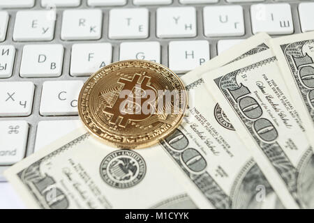 Nuovo denaro virtuale Golden bitcoin moneta e di dollari su una tastiera bianca. Cryptocurrency. Business e concetto di trading. Foto Stock