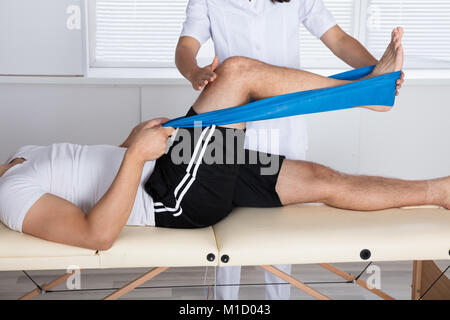 Fisioterapista Aiutare il paziente mentre si estende la sua gamba Foto Stock