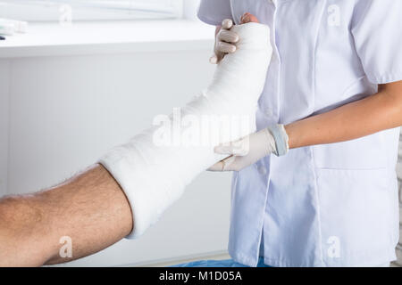 Close-up di un medico donna esame persona infortunata è la gamba in clinica Foto Stock