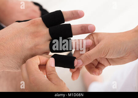 Elevato angolo di visione di un medico mettendo il dito la protezione per manicotto sull'uomo del dito in clinica Foto Stock