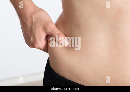 Close-up di una donna di mano schiacciamento eccessivo grasso Stomaco Foto Stock