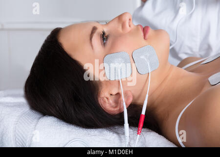 Close-up di una giovane donna sdraiata con elettrodi sul suo viso Foto Stock