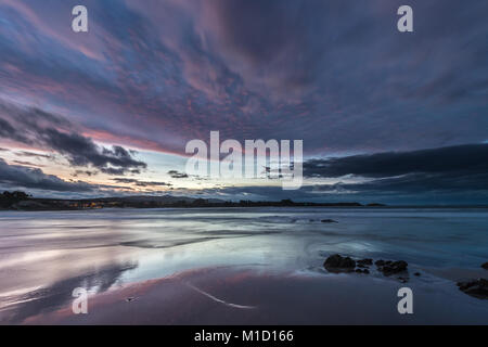 Un tramonto spettacolare sulla spiaggia di Arnao, Asturias, fotografando i diversi colori, forme e texture delle nuvole, riflessa nella sabbia fine Foto Stock