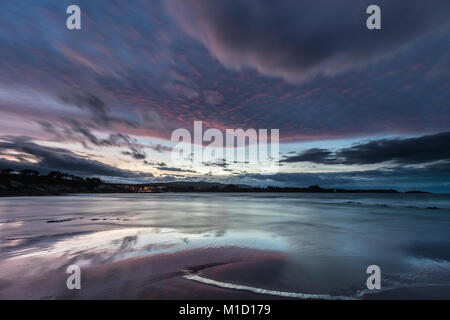 Un tramonto spettacolare sulla spiaggia di Arnao, Asturias, fotografando i diversi colori, forme e texture delle nuvole, riflessa nella sabbia fine Foto Stock