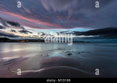 Un tramonto spettacolare sulla spiaggia di Arnao, Asturias, fotografando i diversi colori, forme e texture delle nuvole, riflessa nella sabbia fine Foto Stock