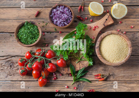 Materie prime e ingredienti per insalata tabulé su tavola in legno rustico Foto Stock