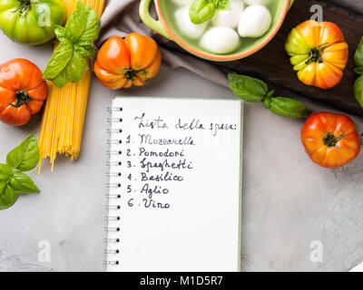 La pasta, il pomodoro, la mozzarella ancora vita sul grigio sfondo rustico. Prodotti tradizionali e cibo lista della spesa per gli spaghetti con i pomodori in italiano Foto Stock