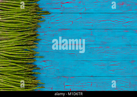 Bordo laterale di freschi Asparagi verdi spears, suggerimenti o spara sulla colorata blu vernice crackle legno con spazio di copia Foto Stock