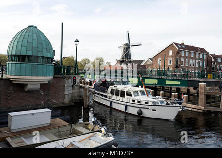 Un ponte levatoio si apre per consentire a una barca di passare sul fiume Spaarne in Haarlem, Olanda. La distanza è il Molen de Adriaan mulino a vento Foto Stock