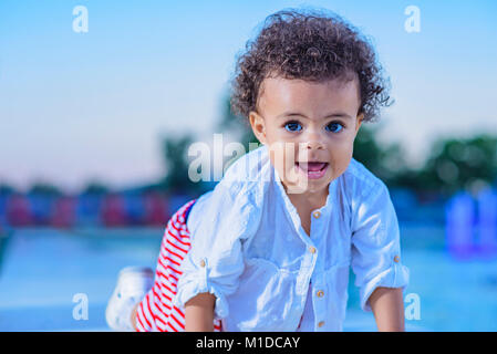 Carino bambina giocando accanto alla fontana di sprinkler Foto Stock