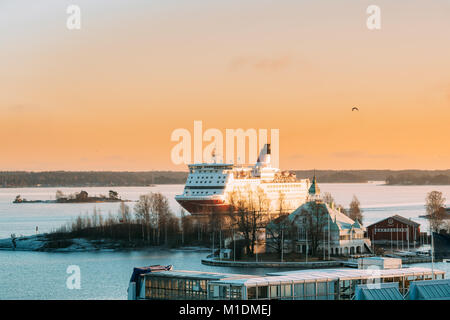 Helsinki, Finlandia. Vista del traghetto moderno battello vela vicino Blekholmen Valkosaari isola sullo sfondo del tramonto Cielo Sunrise.