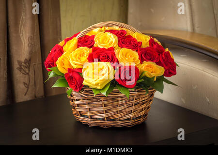 Un bouquet di giallo e rose rosse in un cestello sulla superficie del tavolo. Foto Stock