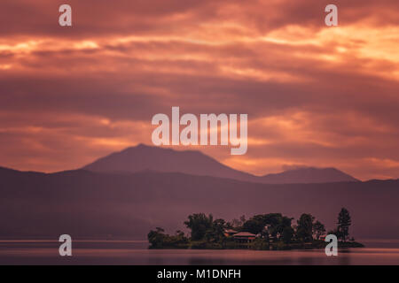 Le piccole di casa sulla piccola isola nel mezzo del meraviglioso Lago Maninjao al tramonto, nell isola di Sumatra, Indonesia Foto Stock