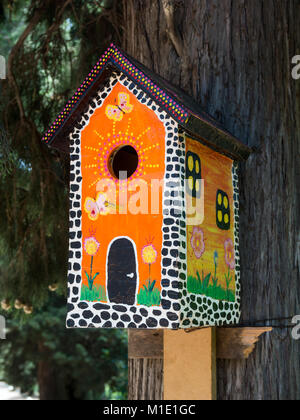 Luminose, dipinta sotto la multi-storey house, birdhouse su un tronco di albero Foto Stock