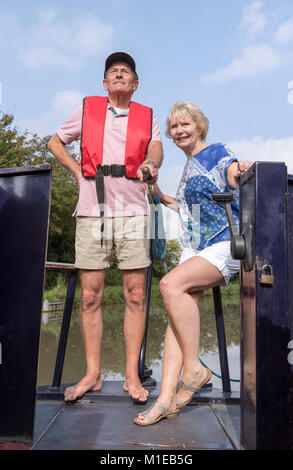 Coppia in una vacanza a galla la sterzatura di un narrowboat utilizzando il timone Foto Stock