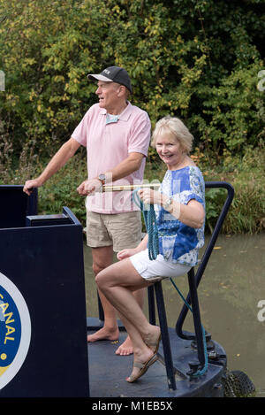 Coppia in una vacanza a galla la sterzatura di un narrowboat utilizzando il timone Foto Stock