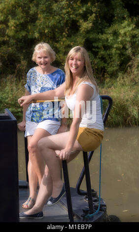 Coppia in una vacanza a galla la sterzatura di un narrowboat utilizzando il timone Foto Stock