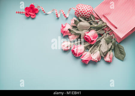 Saluto rosa pallido al mazzo di rose in borsa da shopping con nastro sul turchese sfondo blu, vista dall'alto, copia dello spazio. Vacanze femmina layout. Foto Stock