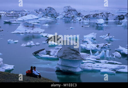 L'Islanda. Jokulsarlon. Iceberg galleggianti nel lago di Jokulsarlon. Turista giovane guardando gli iceberg. Foto Stock