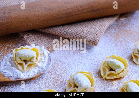 La preparazione di tortellini fatti in casa su un tavolo di legno in cucina. Foto Stock