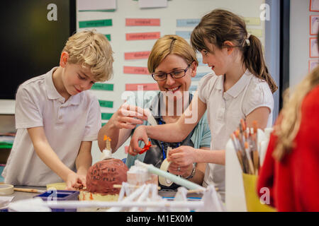 Studenti della scuola primaria stanno facendo arti e mestieri in aula con il loro maestro. Foto Stock