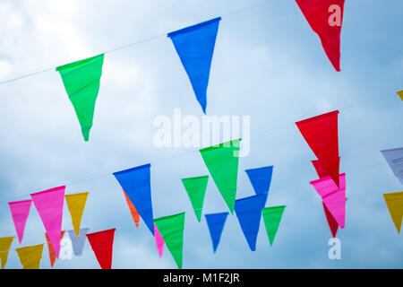 Colorato piccolo bandiere fatte di carta appeso a una fune con cielo blu di sfondo, il fuoco selettivo. Foto Stock