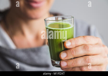 Donna sana inquadratura bere del succo di wheatgrass Foto Stock