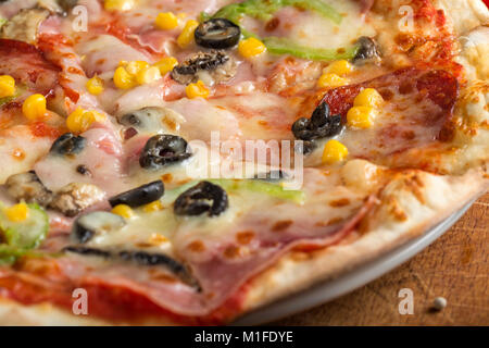 Close up di italiano Capriciosa pizza fatta con salumi e verdure sulla piastra Foto Stock