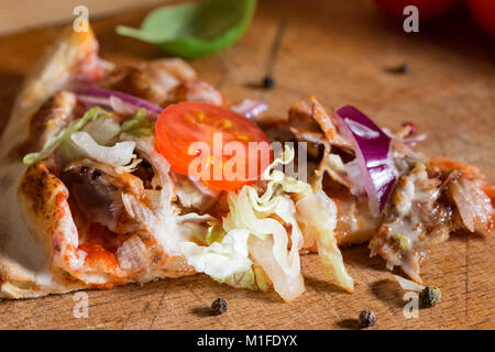 Slace di kebap pizza fatta con carne macinata, cavolo, pomodoro e salsa di aglio su sfondo di legno Foto Stock